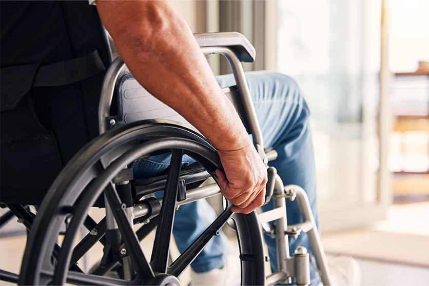 Close-up photo of a man in a wheelchair, whose face is not shown.