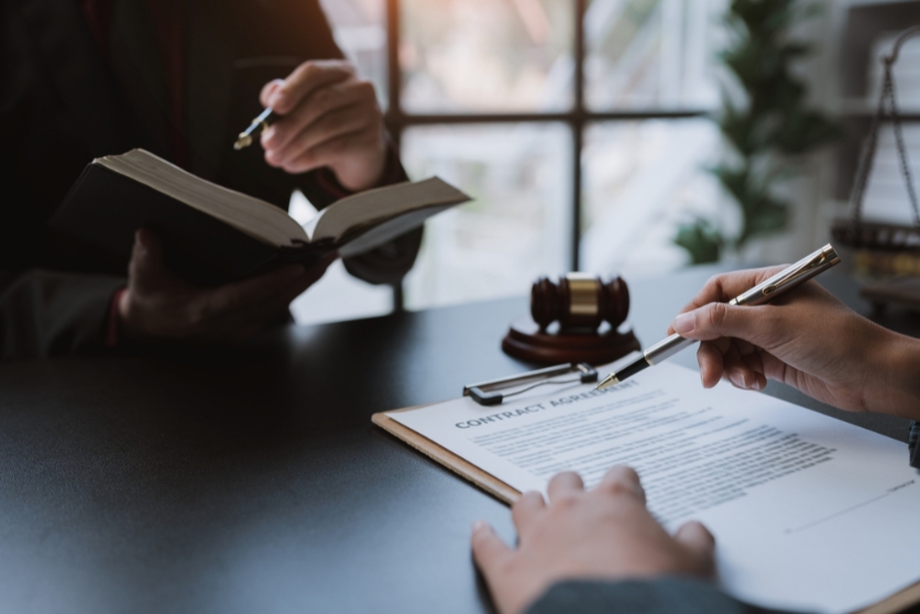 a lawyer discusses statute of limitations with a client, who is signing a contract at a desk.